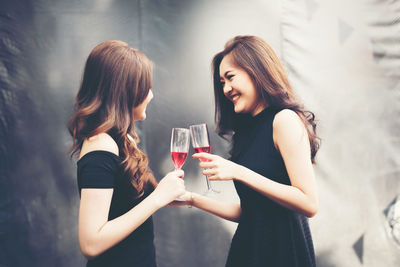 Side view of smiling young friends toasting wineglasses