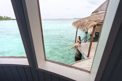 Swimming pool by sea against sky seen through window