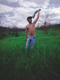 Full length of shirtless man standing on field