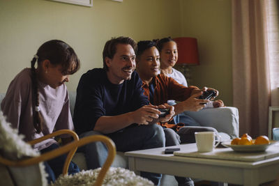 Happy gay men playing video game with daughter while sitting at home