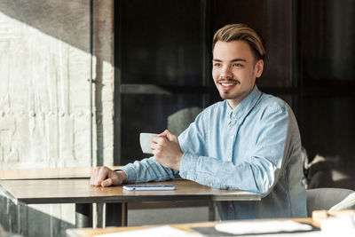 Portrait of happy man sitting on table