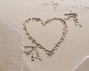 High angle view of heart shape drawn on sand at beach