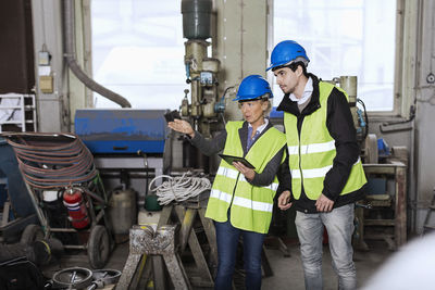 Manual workers with digital tablet discussing in factory