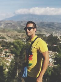 Man wearing sunglasses standing on mountain against sky