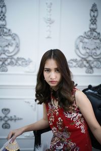 Portrait of beautiful young woman standing against wall