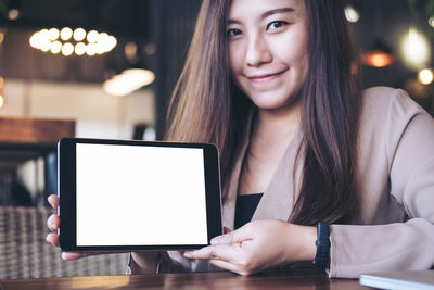 Portrait of businesswoman holding digital tablet at cafe