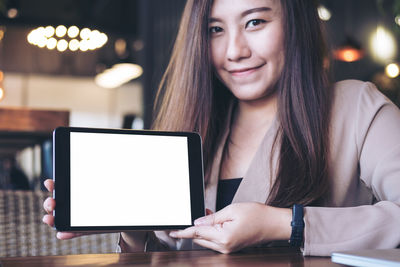 Portrait of young woman using phone on table