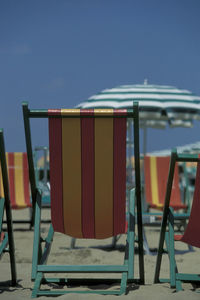 Empty chairs and tables against clear blue sky