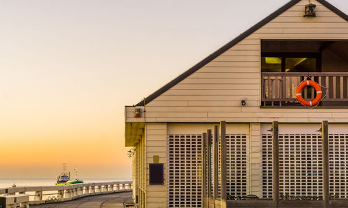 Buildings by sea against clear sky during sunset