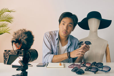 Young man looking at camera on table against wall