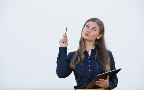 Young woman with digital tablet gesturing against gray background