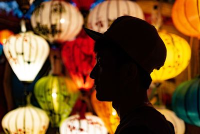 Rear view of man in illuminated market at night