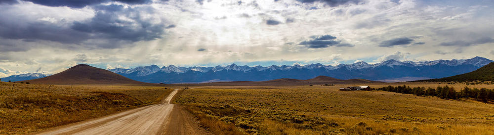 Scenic view of road by mountains against sky