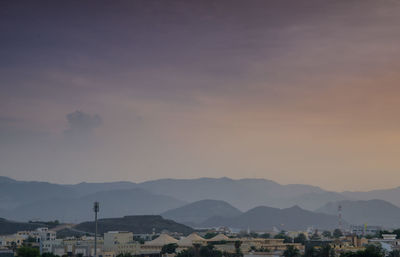 Houses and mountains against sky at sunset