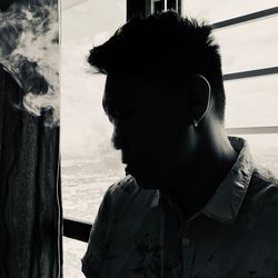 Portrait of young man smoking by window