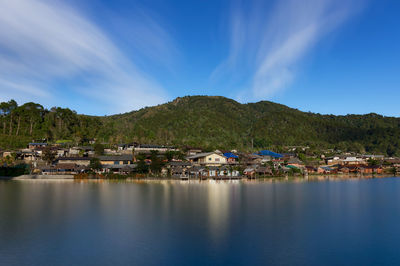 Scenic view of townscape by mountains against sky