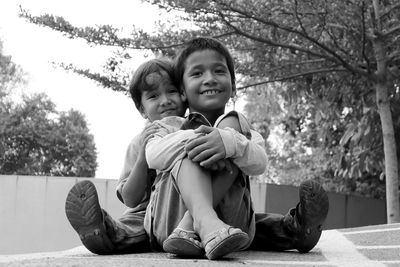 Portrait of smiling siblings sitting outdoors