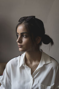 Portrait of young woman looking away against wall