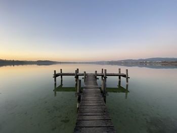 Pier over lake against sky during sunset
