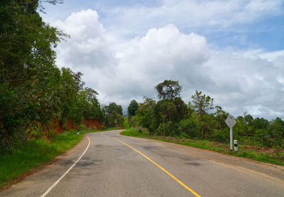 Empty road by trees against sky