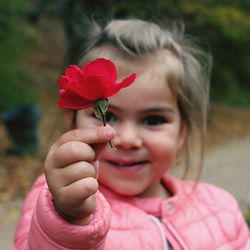 Close-up portrait of a girl holding red flower