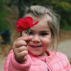 Close-up portrait of girl holding red flower