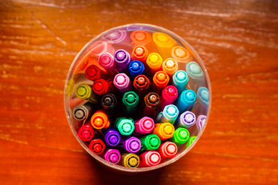 Directly above shot of colorful pens in container on table