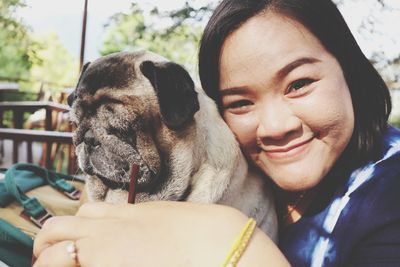 Portrait of smiling woman embracing dog outdoors