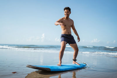 Shirtless man standing in sea against sky