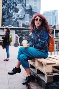 Portrait of young woman sitting at sidewalk cafe in city