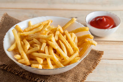 Hot golden french fries with ketchup on wooden background. tasty american fast food.