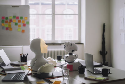 Modern social robots with laptops on desk in innovation lab