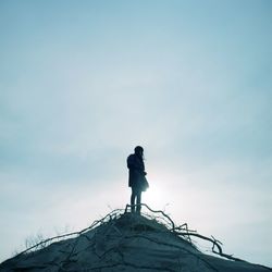 Low angle view of woman on cliff against clear sky