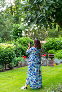 Rear view of woman standing by plants in yard