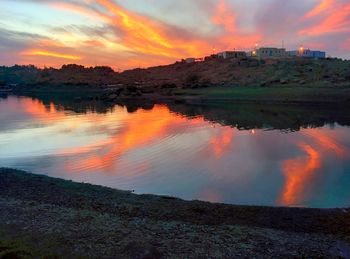 Scenic view of lake against dramatic sky during sunset