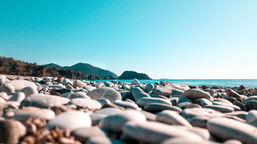 Rocks on beach against clear blue sky