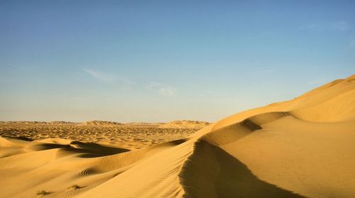 Sand dunes in desert against sky