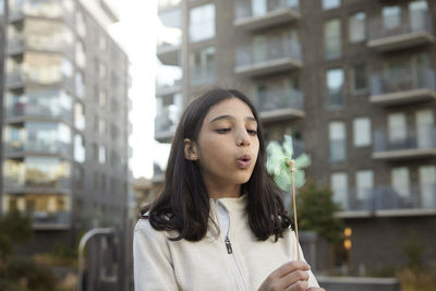 Girl blowing on pinwheel outdoors