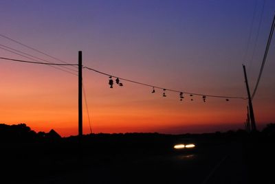 Silhouette power lines against sky during sunset