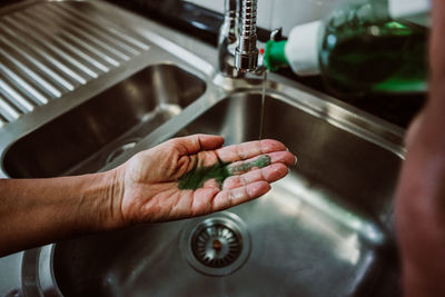 Cropped hands taking liquid in sink