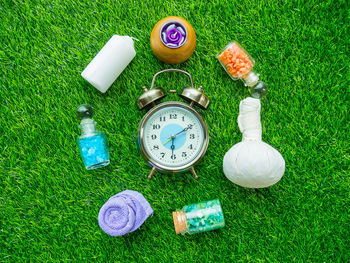 Directly above view of alarm clock and spa accessories on grass
