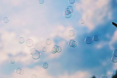 Low angle view of bubbles against rainbow in sky