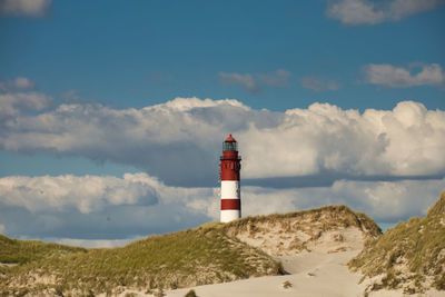 Lighthouse amidst sea and buildings against sky