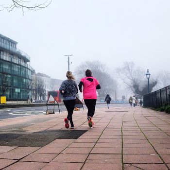 Two women jogging on sidewalk