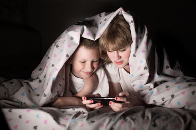 Young woman using mobile phone while lying on bed at home