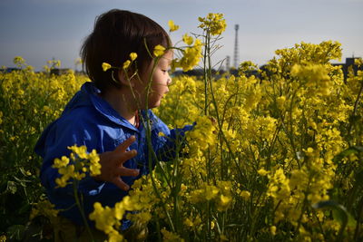 Baby standing on field by yellow flowers