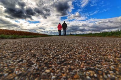 Rear view of men standing on road against sky