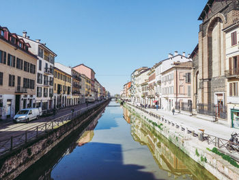 Canal amidst buildings against clear blue sky