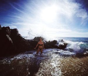 Rear view of woman standing in sea against sky