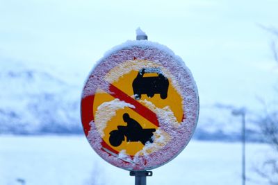 Close-up of snow covered sign against sky